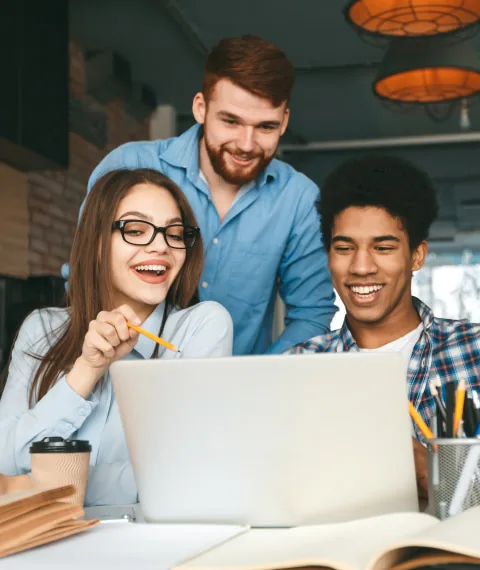 Three students working together at a laptop in a study space